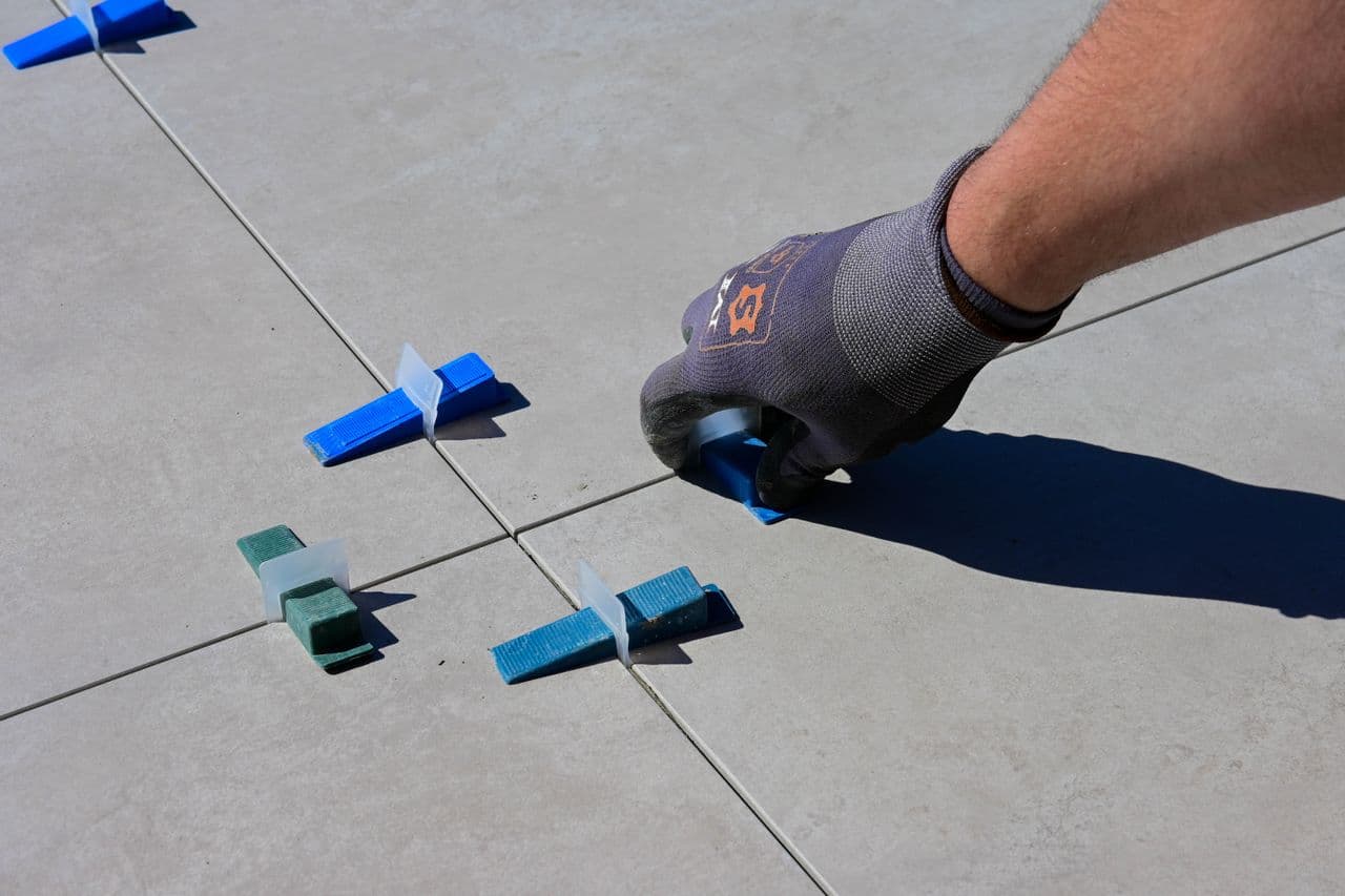 Master tiler installing large format tiles on site